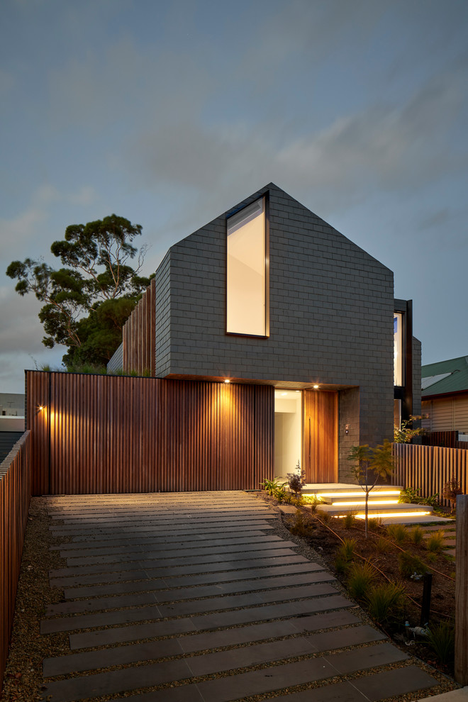 This is an example of a contemporary black house exterior in Melbourne with wood siding, a gable roof and a shingle roof.