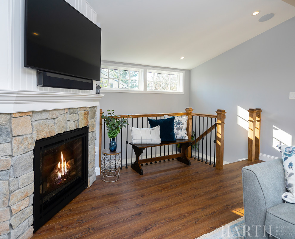 Inspiration for a large classic open plan games room in Philadelphia with a home bar, blue walls, medium hardwood flooring, a standard fireplace, a stone fireplace surround, a wall mounted tv, brown floors and a vaulted ceiling.