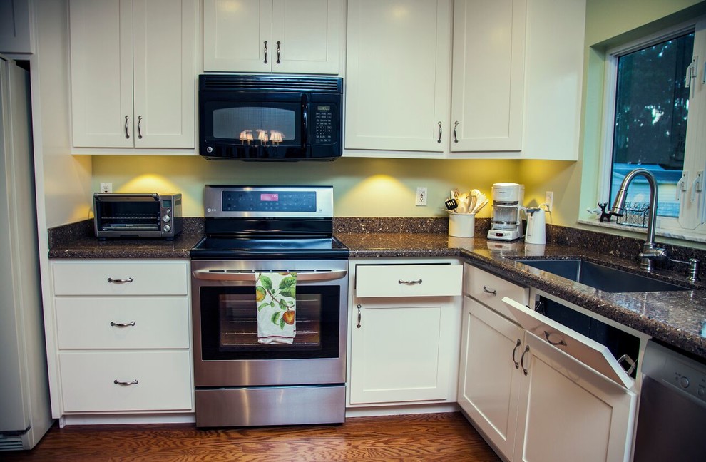 Inspiration for a mid-sized timeless u-shaped medium tone wood floor and brown floor eat-in kitchen remodel in Orlando with an undermount sink, white cabinets, granite countertops, brown backsplash, stone slab backsplash, stainless steel appliances, a peninsula, shaker cabinets and gray countertops