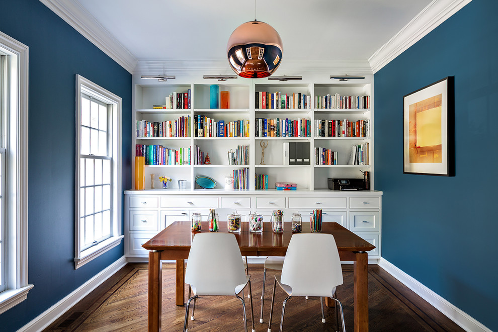 This is an example of a mid-sized transitional study room in New York with blue walls, dark hardwood floors and a freestanding desk.
