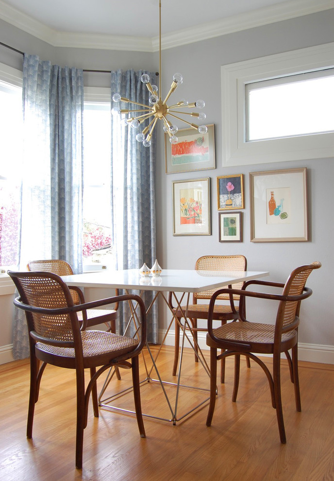 This is an example of an eclectic dining room in San Francisco with grey walls and medium hardwood floors.