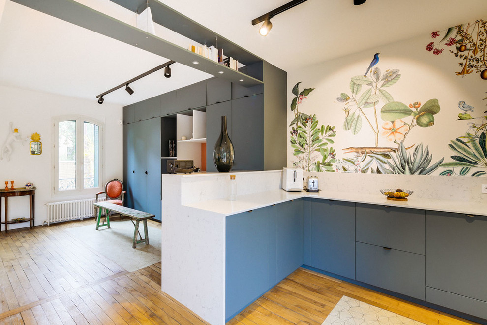 Expansive contemporary single-wall open plan kitchen in Paris with an undermount sink, flat-panel cabinets, blue cabinets, quartzite benchtops, white splashback, black appliances, cement tiles, no island and white benchtop.