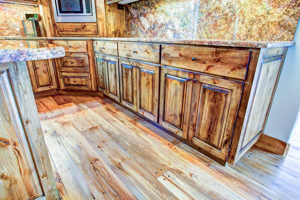 Example of a large mountain style u-shaped medium tone wood floor kitchen pantry design with a drop-in sink, glass-front cabinets, medium tone wood cabinets, beige backsplash, stainless steel appliances and an island
