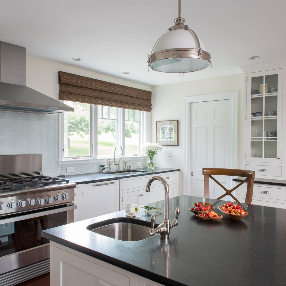 Large transitional u-shaped medium tone wood floor enclosed kitchen photo with an undermount sink, recessed-panel cabinets, white cabinets, granite countertops, blue backsplash, glass tile backsplash, stainless steel appliances and an island