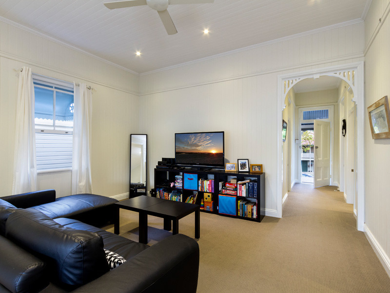 This is an example of a small contemporary open concept living room in Brisbane with beige walls, carpet and a freestanding tv.