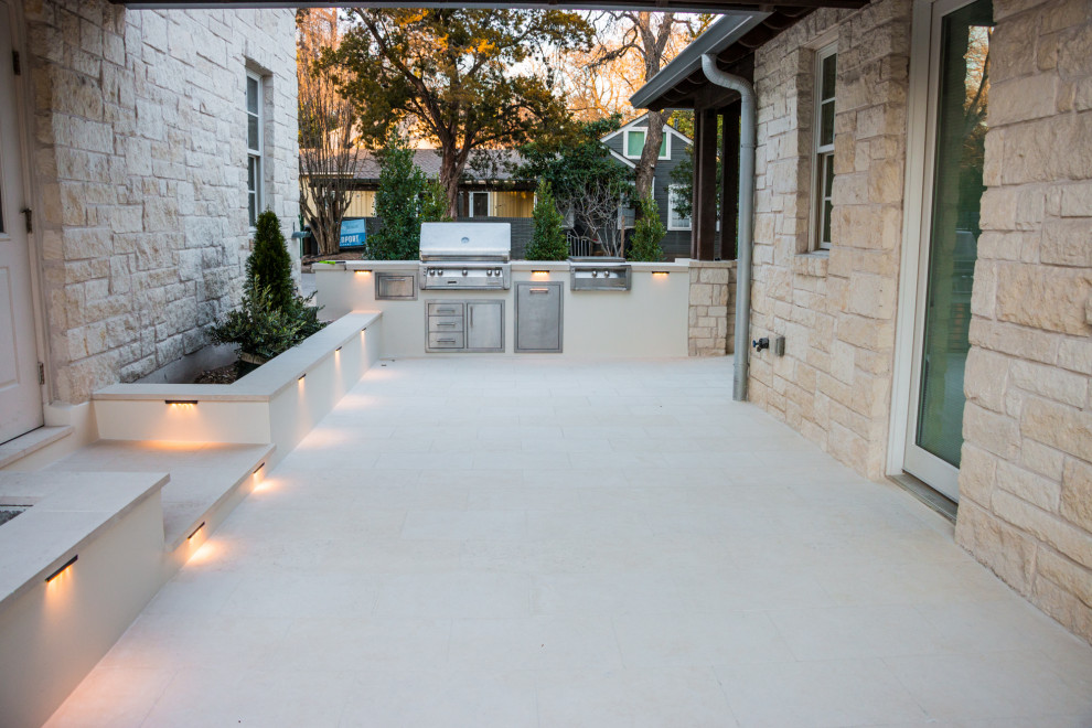Cette photo montre une grande terrasse arrière moderne avec une cuisine d'été et des pavés en pierre naturelle.