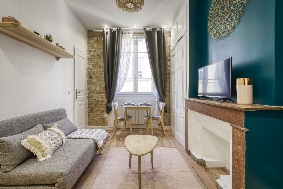 Foto de salón abierto nórdico pequeño con paredes verdes, suelo de madera en tonos medios, todas las chimeneas, piedra de revestimiento y televisor independiente