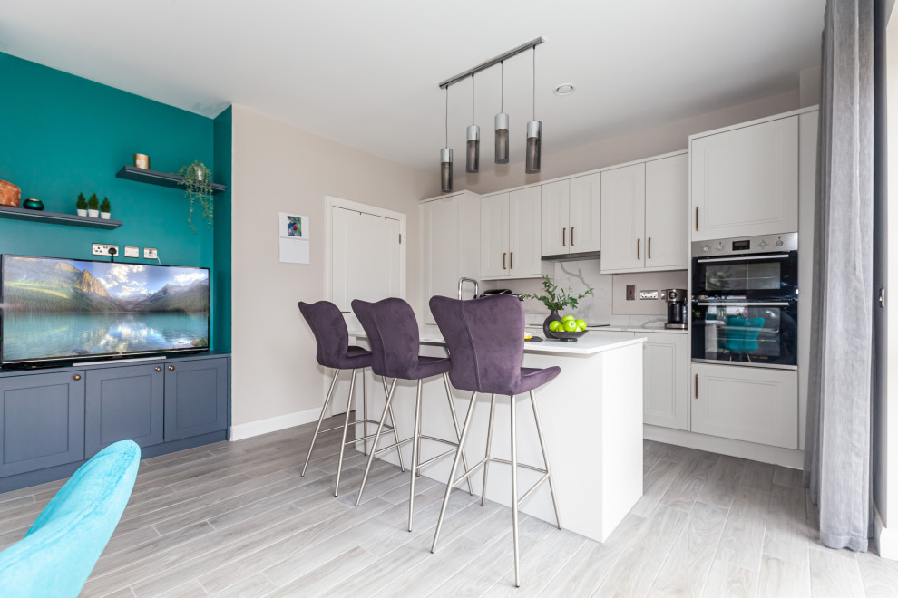 Mid-sized modern single-wall eat-in kitchen in Dublin with an integrated sink, white cabinets, quartzite benchtops, multi-coloured splashback, panelled appliances, ceramic floors, with island, grey floor and multi-coloured benchtop.