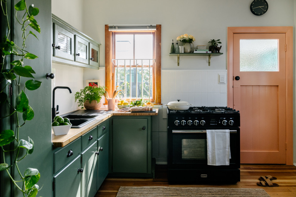 Idée de décoration pour une petite cuisine vintage fermée avec un plan de travail en surface solide, une crédence blanche, une crédence en feuille de verre, un sol orange et un plan de travail vert.