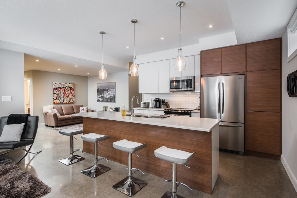 Inspiration for a mid-sized modern single-wall open plan kitchen in Toronto with flat-panel cabinets, white cabinets, white splashback, ceramic splashback, stainless steel appliances, concrete floors, with island, a double-bowl sink and quartzite benchtops.