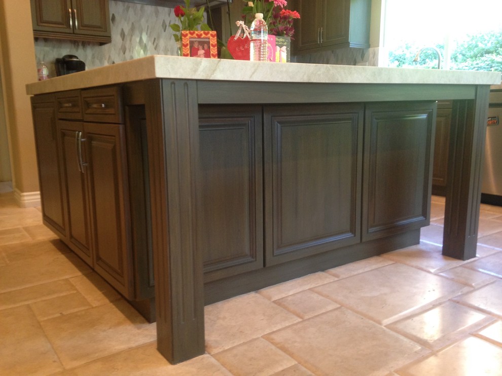 This is an example of a mid-sized contemporary eat-in kitchen in Orange County with recessed-panel cabinets, dark wood cabinets and with island.