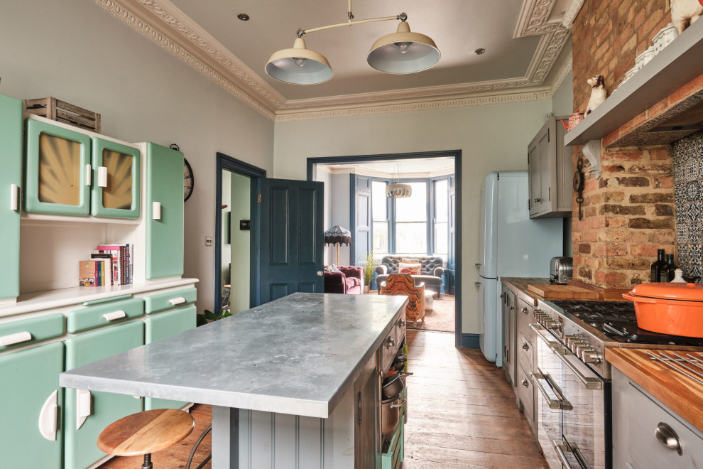 Design ideas for a large eclectic galley open plan kitchen in London with a farmhouse sink, shaker cabinets, grey cabinets, zinc benchtops, blue splashback, ceramic splashback, coloured appliances, medium hardwood floors, with island and grey benchtop.