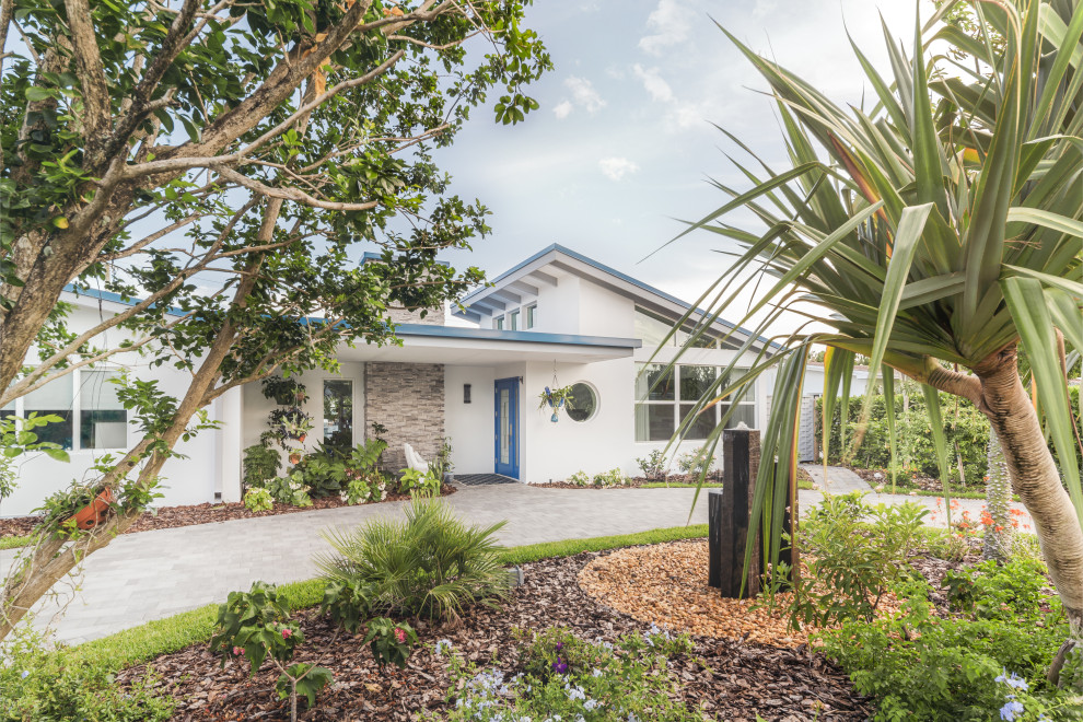 Midcentury one-storey stucco white house exterior in Miami with a shed roof, a metal roof and a blue roof.