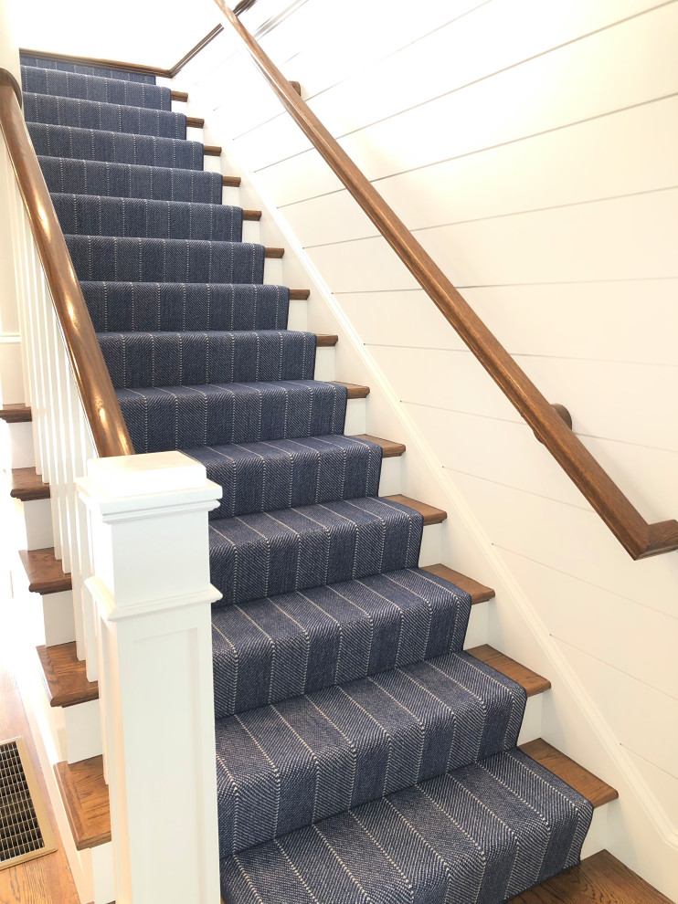 Medium sized beach style carpeted straight wood railing staircase in Boston with marble risers.