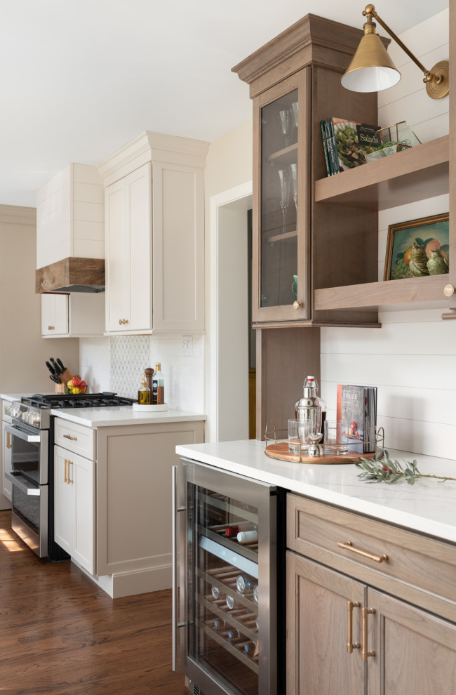Design ideas for a small traditional galley kitchen/diner in Chicago with a belfast sink, flat-panel cabinets, white cabinets, engineered stone countertops, white splashback, ceramic splashback, stainless steel appliances, medium hardwood flooring, an island, brown floors and white worktops.