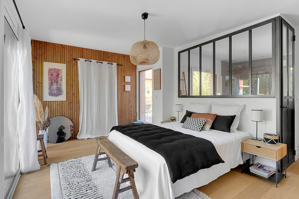 This is an example of a contemporary bedroom in Toulouse with brown walls, light hardwood floors, beige floor and wood walls.