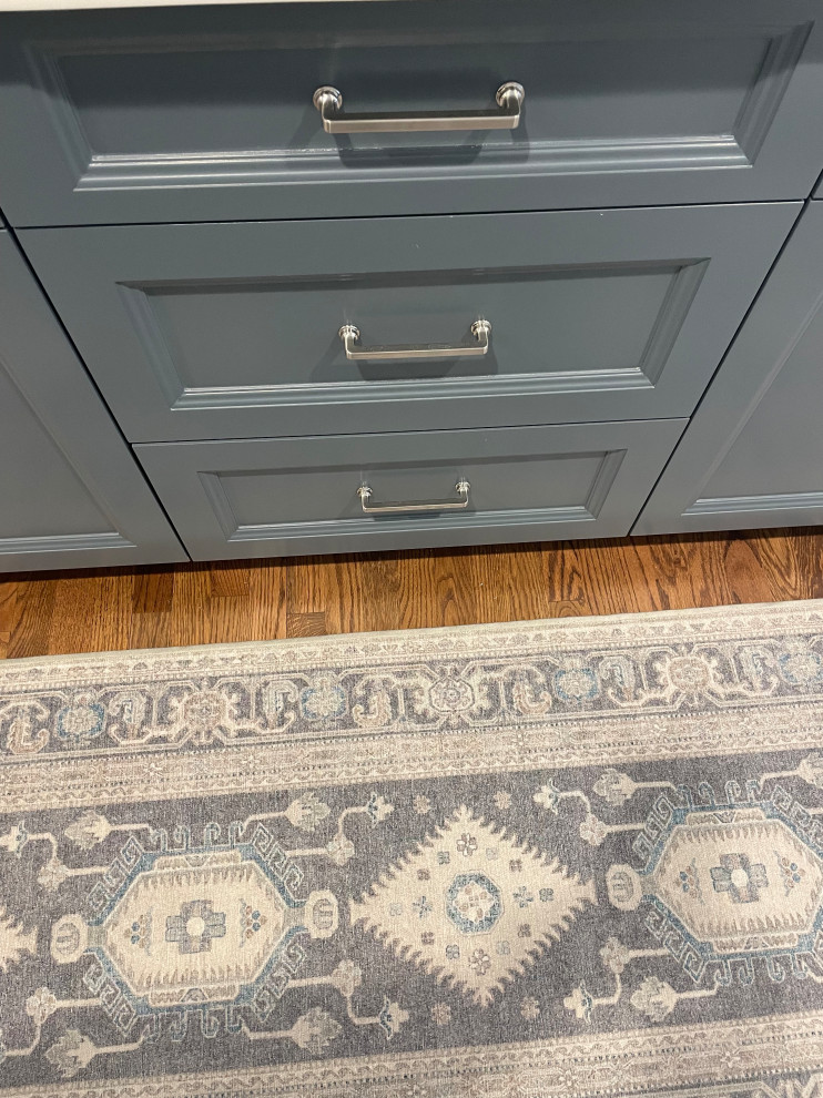 Example of a transitional light wood floor kitchen design in Omaha with blue cabinets, white backsplash, subway tile backsplash, stainless steel appliances, an island and white countertops