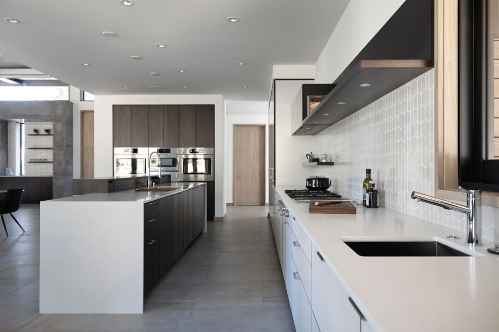 Inspiration for a large modern l-shaped open plan kitchen in San Francisco with an undermount sink, flat-panel cabinets, white cabinets, quartz benchtops, white splashback, ceramic splashback, panelled appliances, porcelain floors and with island.