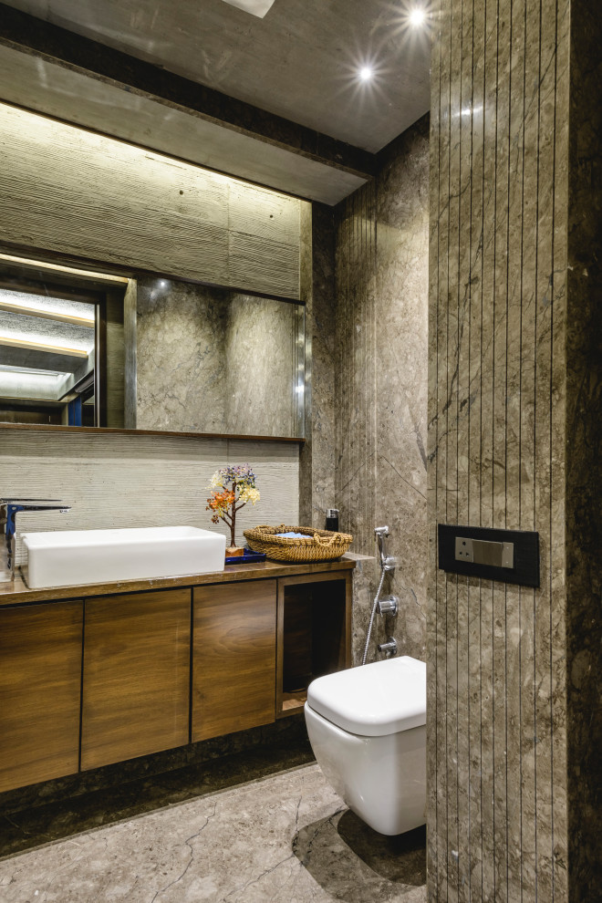 Mid-sized contemporary powder room in Other with flat-panel cabinets, medium wood cabinets, gray tile, a vessel sink, grey floor, brown benchtops and a floating vanity.