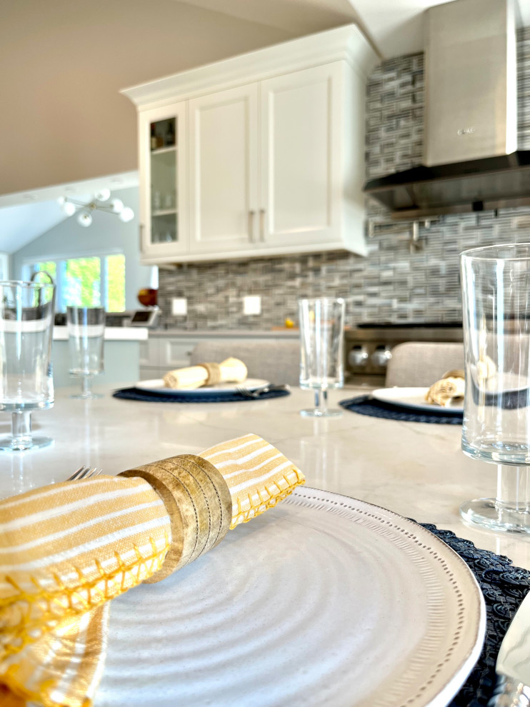 Eat-in kitchen - transitional single-wall vinyl floor, brown floor and vaulted ceiling eat-in kitchen idea with an undermount sink, shaker cabinets, white cabinets, quartz countertops, blue backsplash, glass sheet backsplash, stainless steel appliances, an island and gray countertops