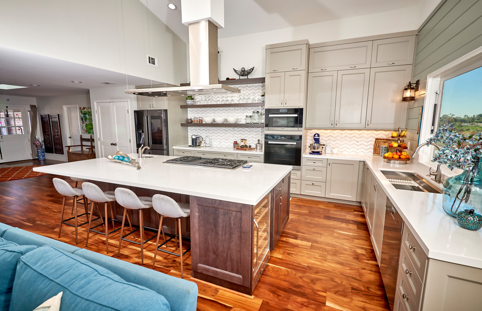 Example of a large transitional l-shaped medium tone wood floor and brown floor open concept kitchen design in Denver with an undermount sink, recessed-panel cabinets, gray cabinets, quartz countertops, white backsplash, marble backsplash, stainless steel appliances, an island and white countertops