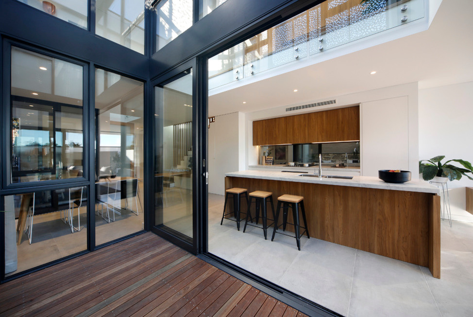 Photo of a large contemporary galley open plan kitchen in Sydney with porcelain floors, a double-bowl sink, flat-panel cabinets, medium wood cabinets, marble benchtops and with island.