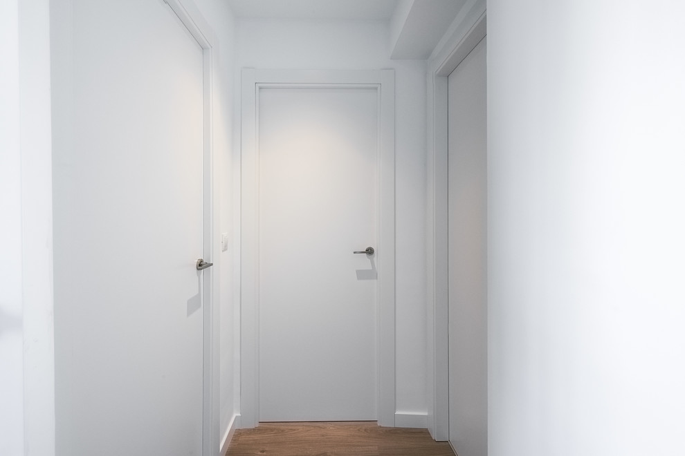 Design ideas for a mid-sized contemporary hallway in Valencia with white walls, laminate floors and brown floor.