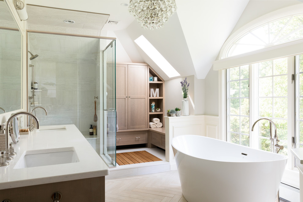Photo of a transitional master bathroom in Boston with shaker cabinets, medium wood cabinets, a freestanding tub, a corner shower, beige tile, white walls, an undermount sink, beige floor, a hinged shower door and white benchtops.