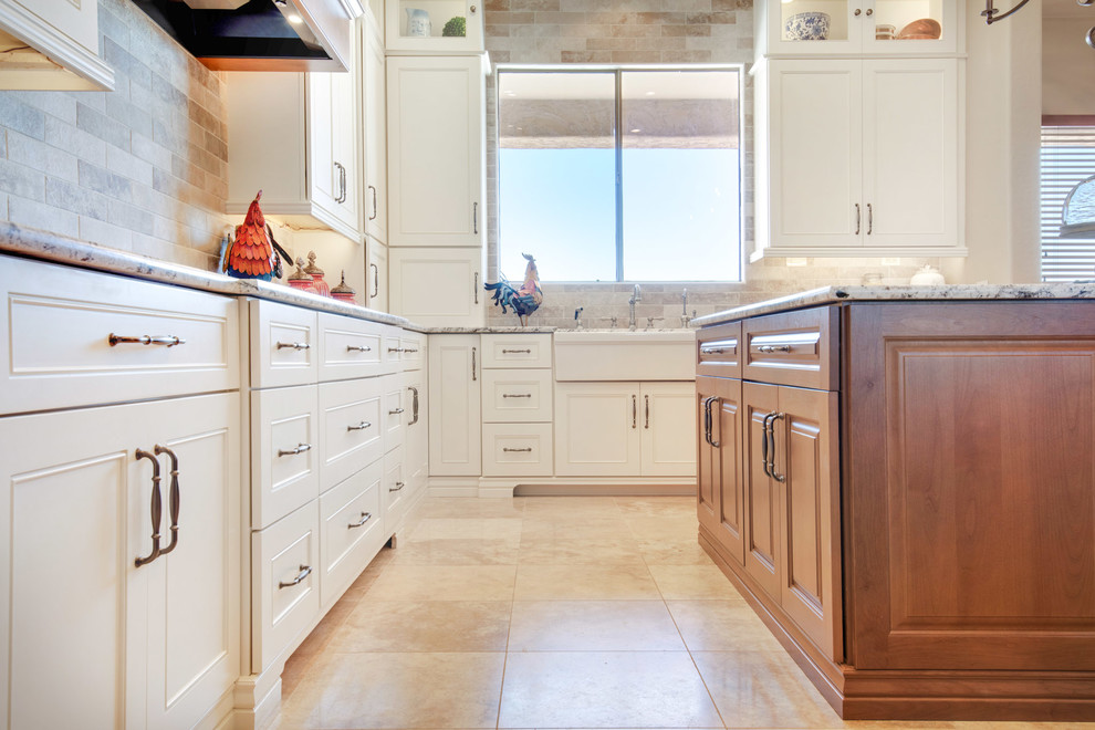 Inspiration for a large transitional u-shaped travertine floor and beige floor open concept kitchen remodel in Phoenix with a farmhouse sink, recessed-panel cabinets, white cabinets, granite countertops, gray backsplash, porcelain backsplash, stainless steel appliances, an island and multicolored countertops