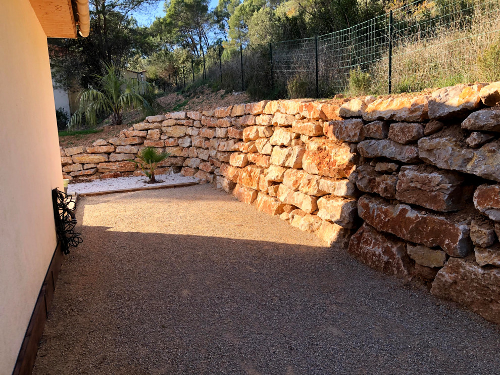Esempio di un grande giardino tradizionale con un muro di contenimento, un pendio, una collina o una riva e recinzione in pietra
