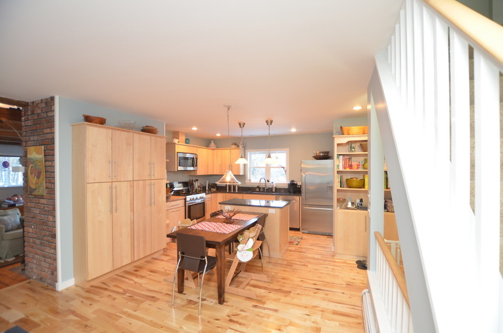 This is an example of a mid-sized contemporary eat-in kitchen in Burlington with an undermount sink, flat-panel cabinets, light wood cabinets, granite benchtops, stone slab splashback, stainless steel appliances, light hardwood floors and with island.