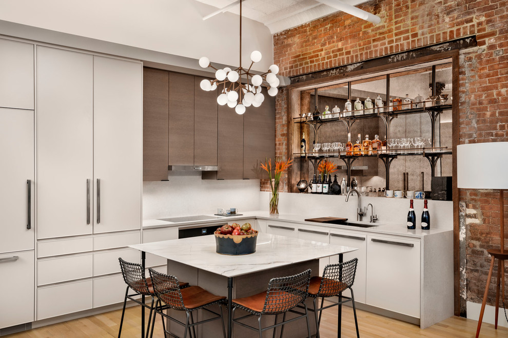 This is an example of an industrial l-shaped kitchen in New York with an undermount sink, flat-panel cabinets, white cabinets, white splashback, light hardwood floors, with island and white benchtop.
