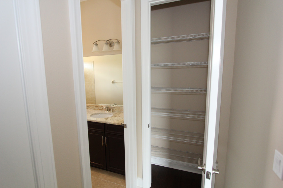 Design ideas for a large transitional gender-neutral built-in wardrobe in Orlando with dark hardwood floors and brown floor.