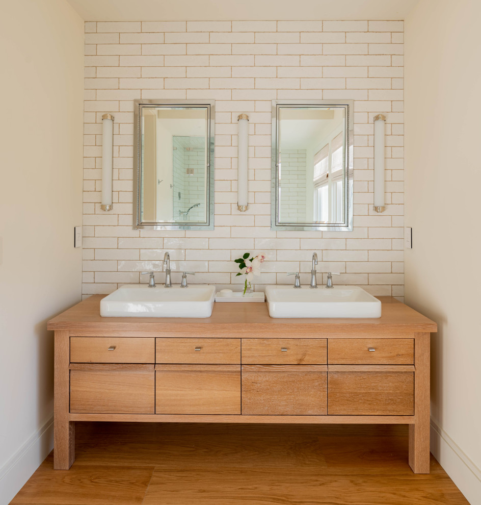 This is an example of a mid-sized transitional master bathroom in Other with light wood cabinets, a corner shower, a two-piece toilet, white tile, ceramic tile, white walls, light hardwood floors, a vessel sink, wood benchtops and a hinged shower door.