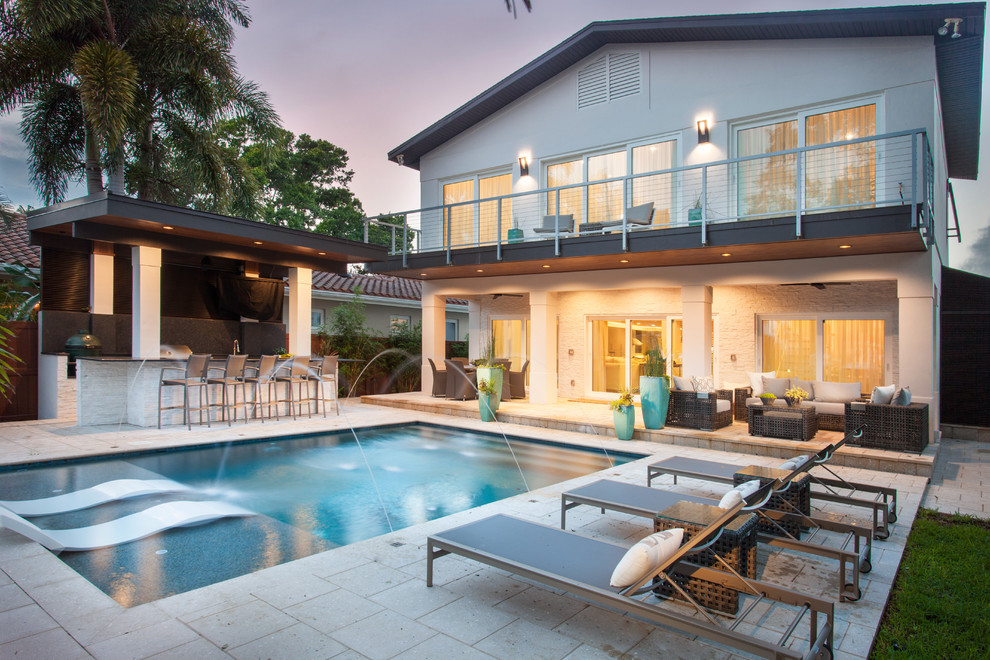 Inspiration for a large contemporary backyard rectangular pool in Tampa with natural stone pavers and a water feature.