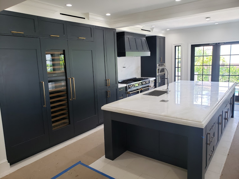 This is an example of a large contemporary galley eat-in kitchen in Miami with a single-bowl sink, raised-panel cabinets, blue cabinets, quartzite benchtops, beige splashback, granite splashback, panelled appliances, ceramic floors, with island, beige floor and beige benchtop.