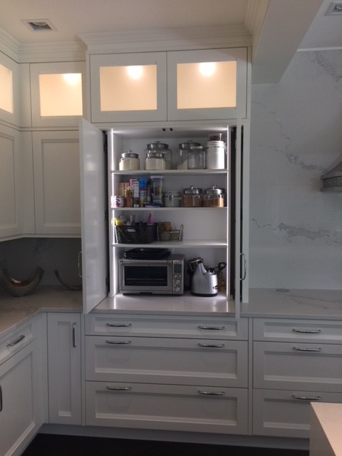 Example of a large transitional u-shaped vinyl floor and black floor eat-in kitchen design with a farmhouse sink, recessed-panel cabinets, white cabinets, white backsplash, paneled appliances, an island, white countertops, quartz countertops and quartz backsplash