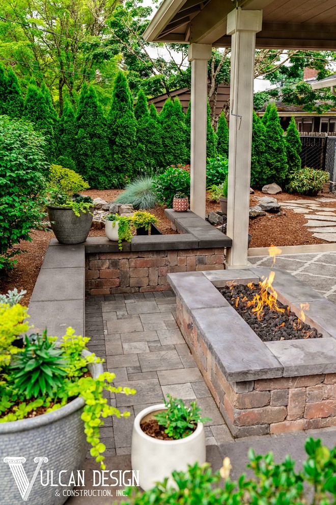 Photo of a mid-sized contemporary backyard patio in Portland with a fire feature, brick pavers and a roof extension.