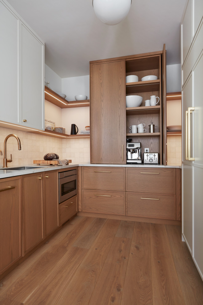 Inspiration for a large contemporary galley kitchen pantry in Toronto with a submerged sink, flat-panel cabinets, light wood cabinets, engineered stone countertops, white splashback, integrated appliances, light hardwood flooring, an island, brown floors and white worktops.