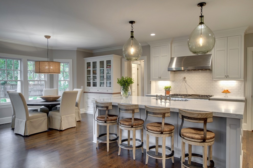Design ideas for a transitional eat-in kitchen in Minneapolis with recessed-panel cabinets, white cabinets, white splashback, subway tile splashback, stainless steel appliances, medium hardwood floors and with island.