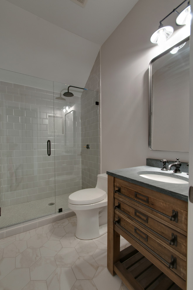Design ideas for a mid-sized transitional 3/4 bathroom in Nashville with furniture-like cabinets, an alcove shower, a one-piece toilet, gray tile, ceramic tile, grey walls, ceramic floors, an undermount sink, medium wood cabinets, soapstone benchtops, white floor, a hinged shower door and grey benchtops.