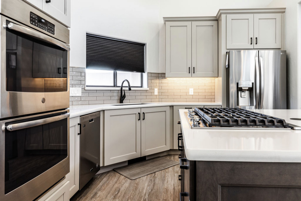 Example of a large transitional u-shaped vinyl floor and gray floor eat-in kitchen design with an undermount sink, shaker cabinets, gray cabinets, quartzite countertops, green backsplash, subway tile backsplash, stainless steel appliances, an island and white countertops