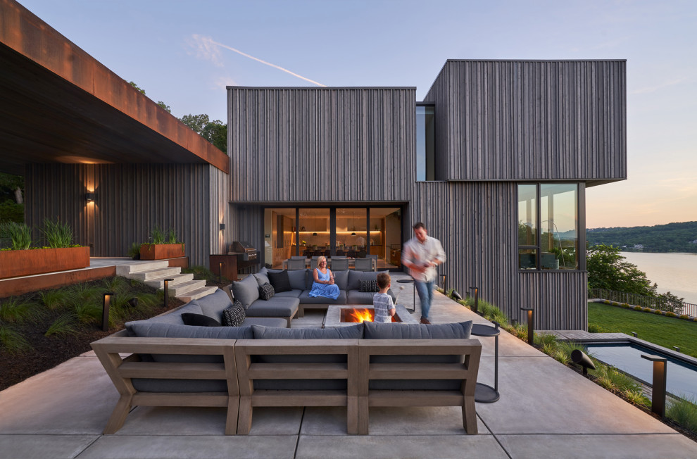 Cette image montre une terrasse latérale minimaliste de taille moyenne avec un foyer extérieur et une dalle de béton.