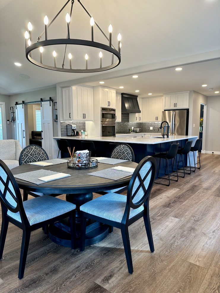 Mid-sized transitional medium tone wood floor, brown floor and vaulted ceiling kitchen/dining room combo photo with white walls