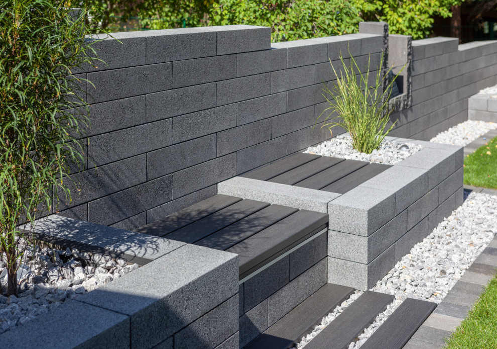 Design ideas for a modern garden with a retaining wall and concrete pavers.