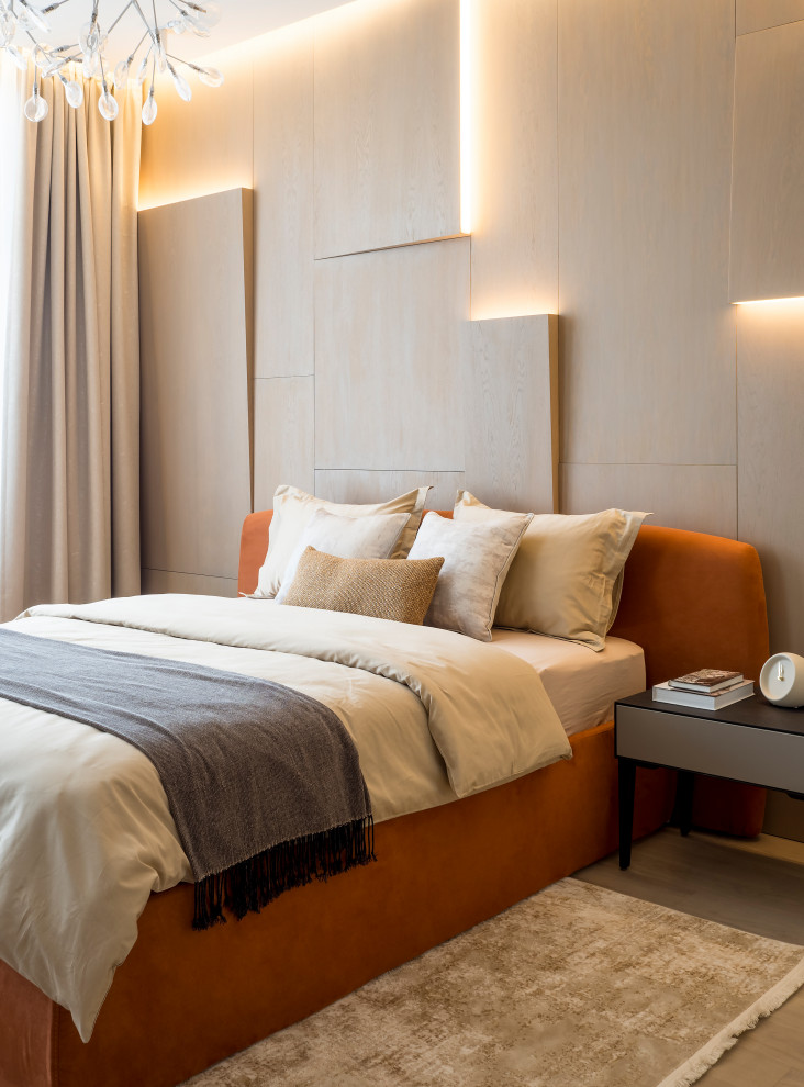 Modelo de dormitorio principal contemporáneo con parades naranjas y suelo de madera en tonos medios