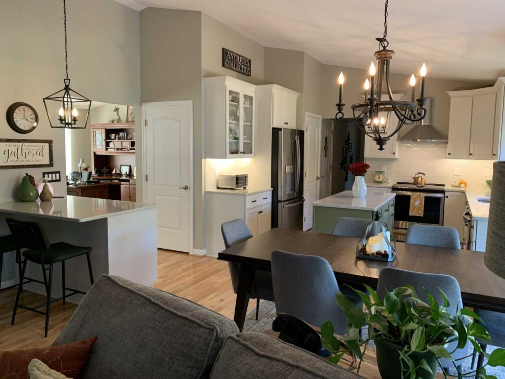 Mid-sized transitional l-shaped light wood floor eat-in kitchen photo in Baltimore with an undermount sink, shaker cabinets, green cabinets, quartz countertops, white backsplash, subway tile backsplash, stainless steel appliances, an island and multicolored countertops