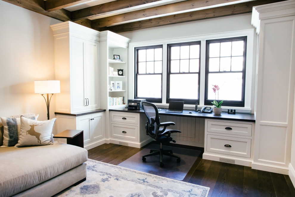 Photo of a large traditional home office in Toronto with a library, white walls, dark hardwood floors, a built-in desk and brown floor.