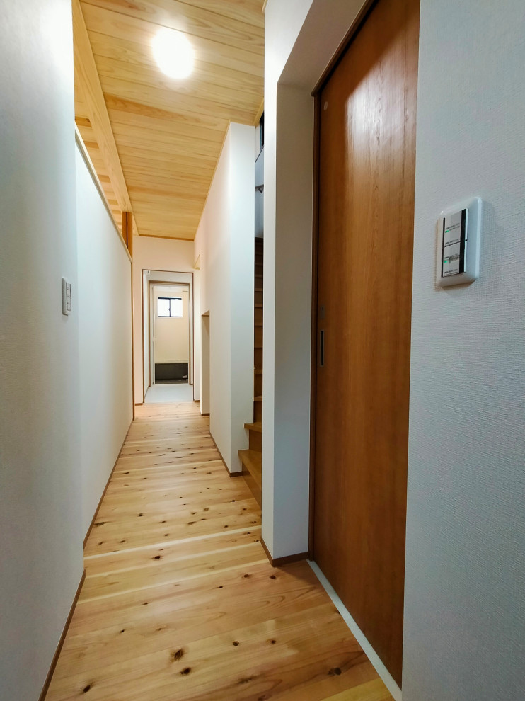 This is an example of a mid-sized hallway in Other with white walls, medium hardwood floors, brown floor, wood and wallpaper.