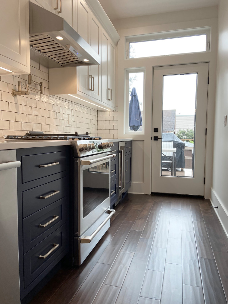 Mid-sized traditional single-wall eat-in kitchen in Seattle with a farmhouse sink, quartz benchtops, white splashback, ceramic splashback, stainless steel appliances, medium hardwood floors, brown floor, white benchtop, shaker cabinets, black cabinets and no island.